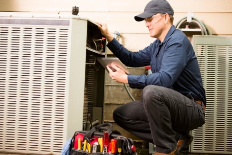 HVAC tech repairing a central air conditioner condenser unit