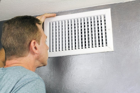 A homeowner examining their air vent