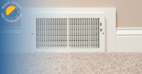 A white vent on the bottom of a wall in between molding