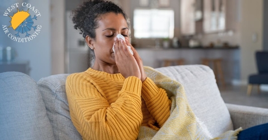 A woman sitting on a couch and holding a tissue to her face with both hands