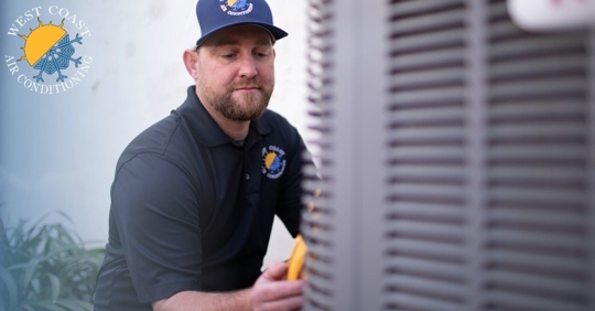 A man holding an ac tester next to a gray condenser unit