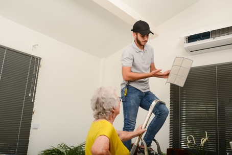 Electrician replacing air filter on an indoor unit
